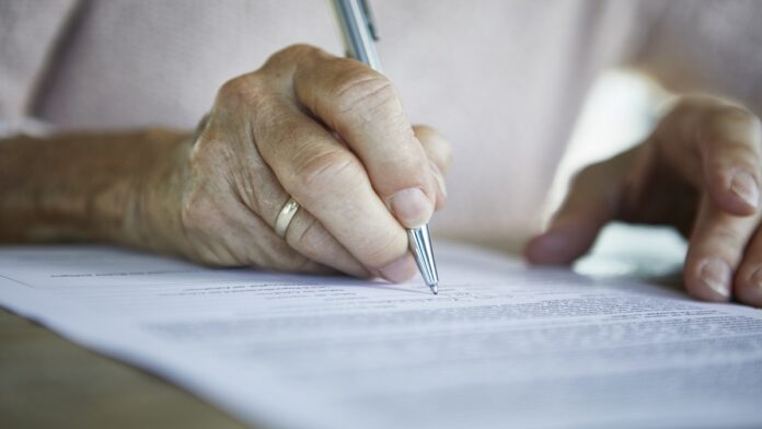 Senior woman's hand signing a document, close-up